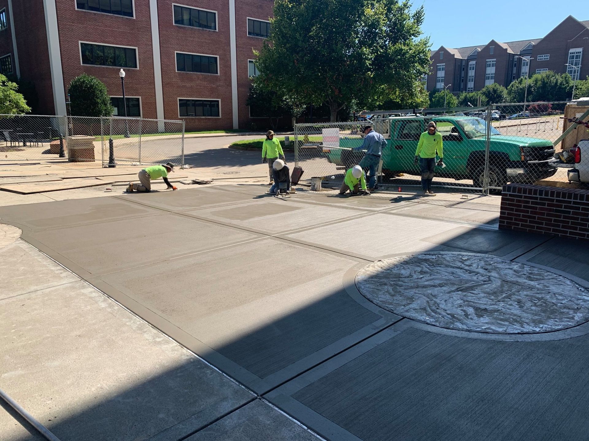 A group of construction workers are working on a concrete driveway.