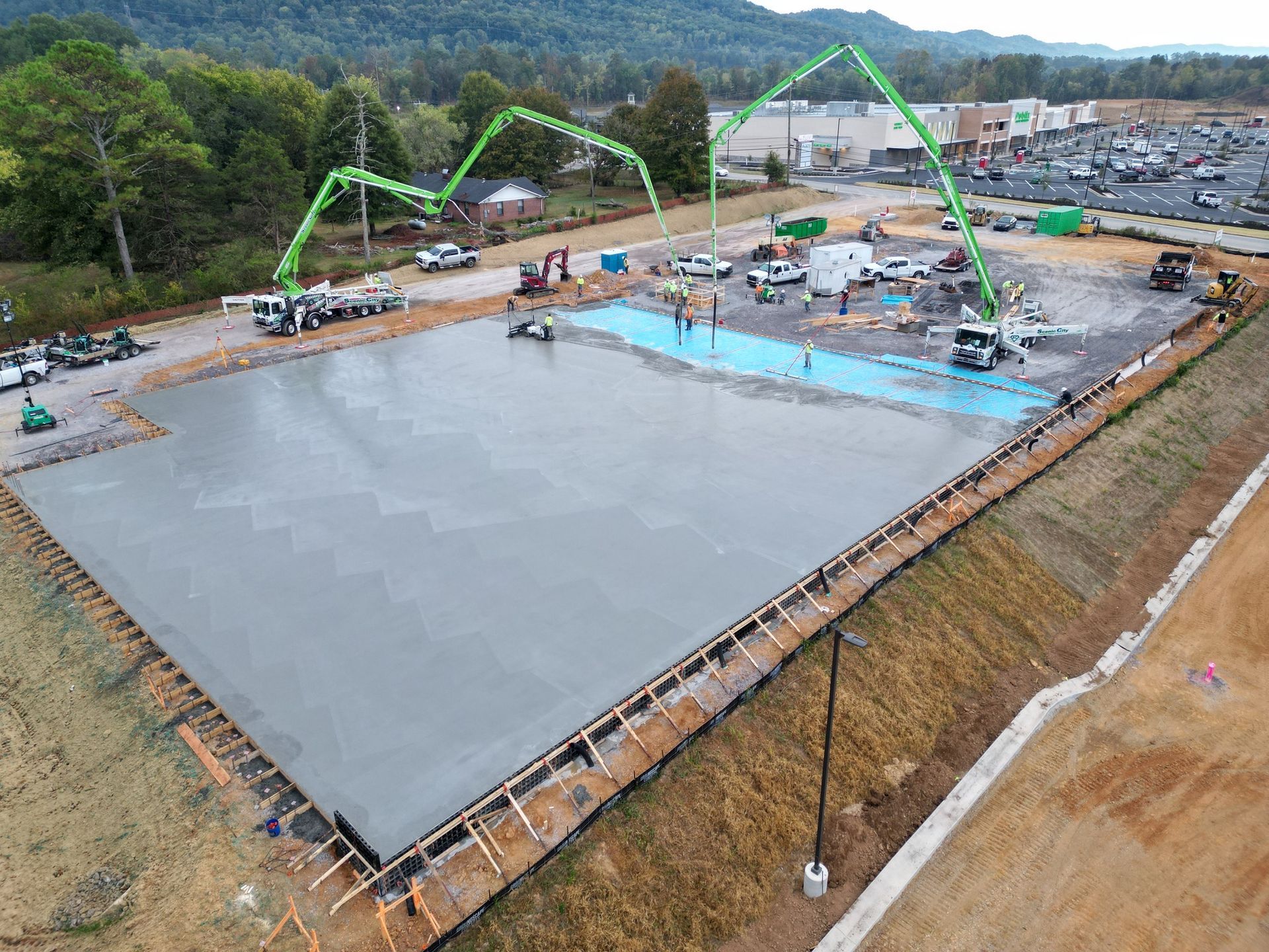 An aerial view of a large concrete slab being poured on a construction site.