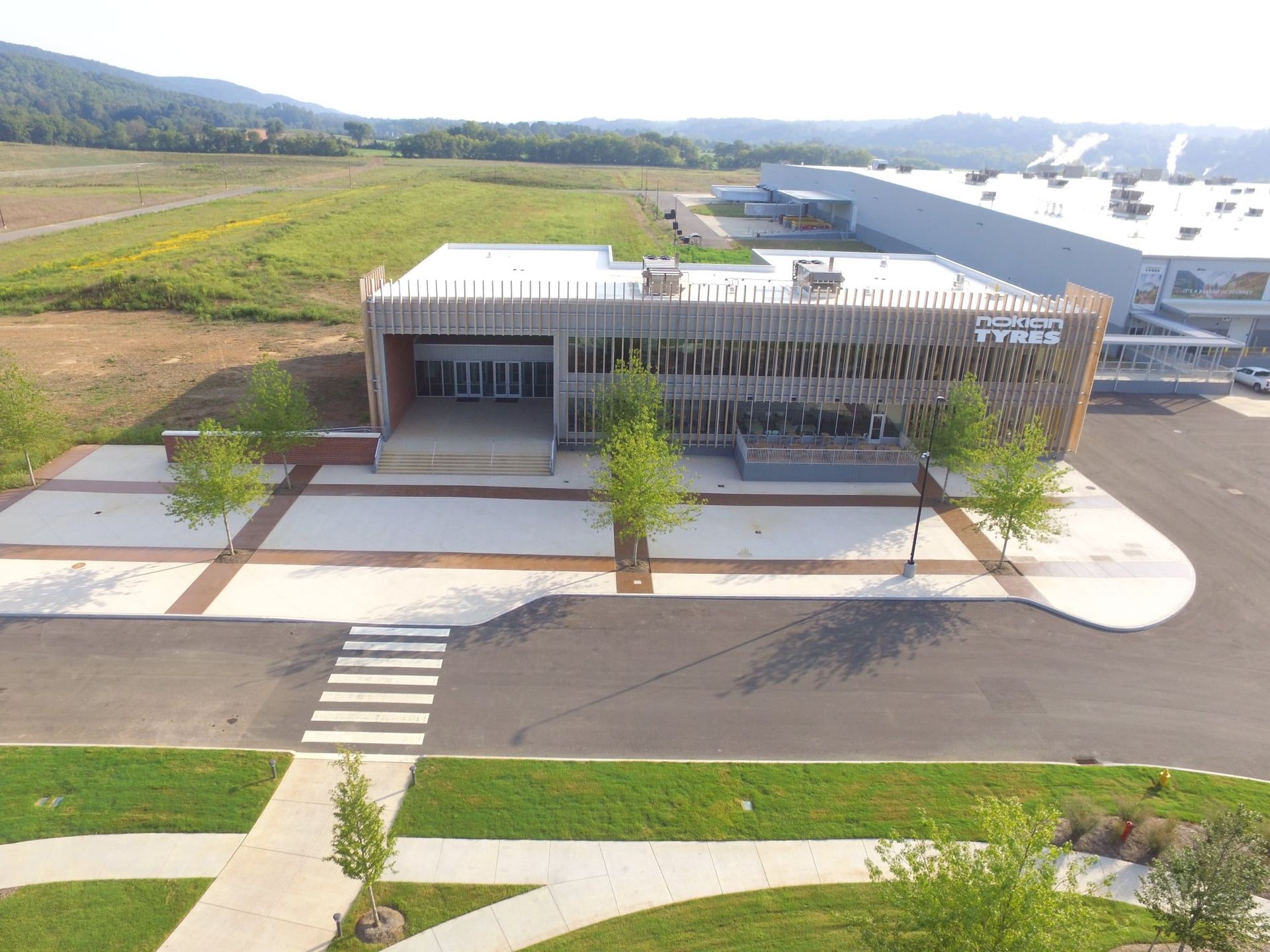 An aerial view of a building with a lot of grass and trees in front of it.