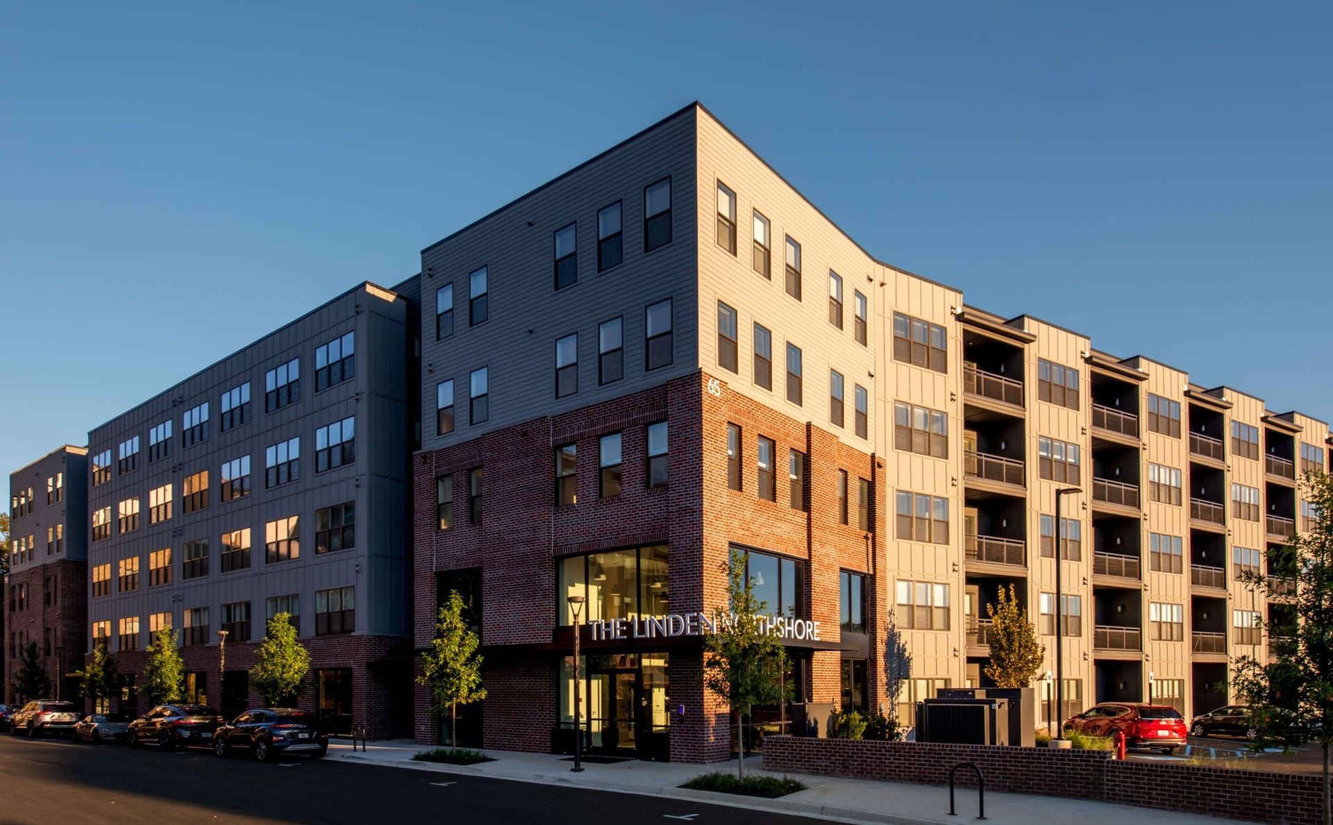 A large apartment building with cars parked in front of it.