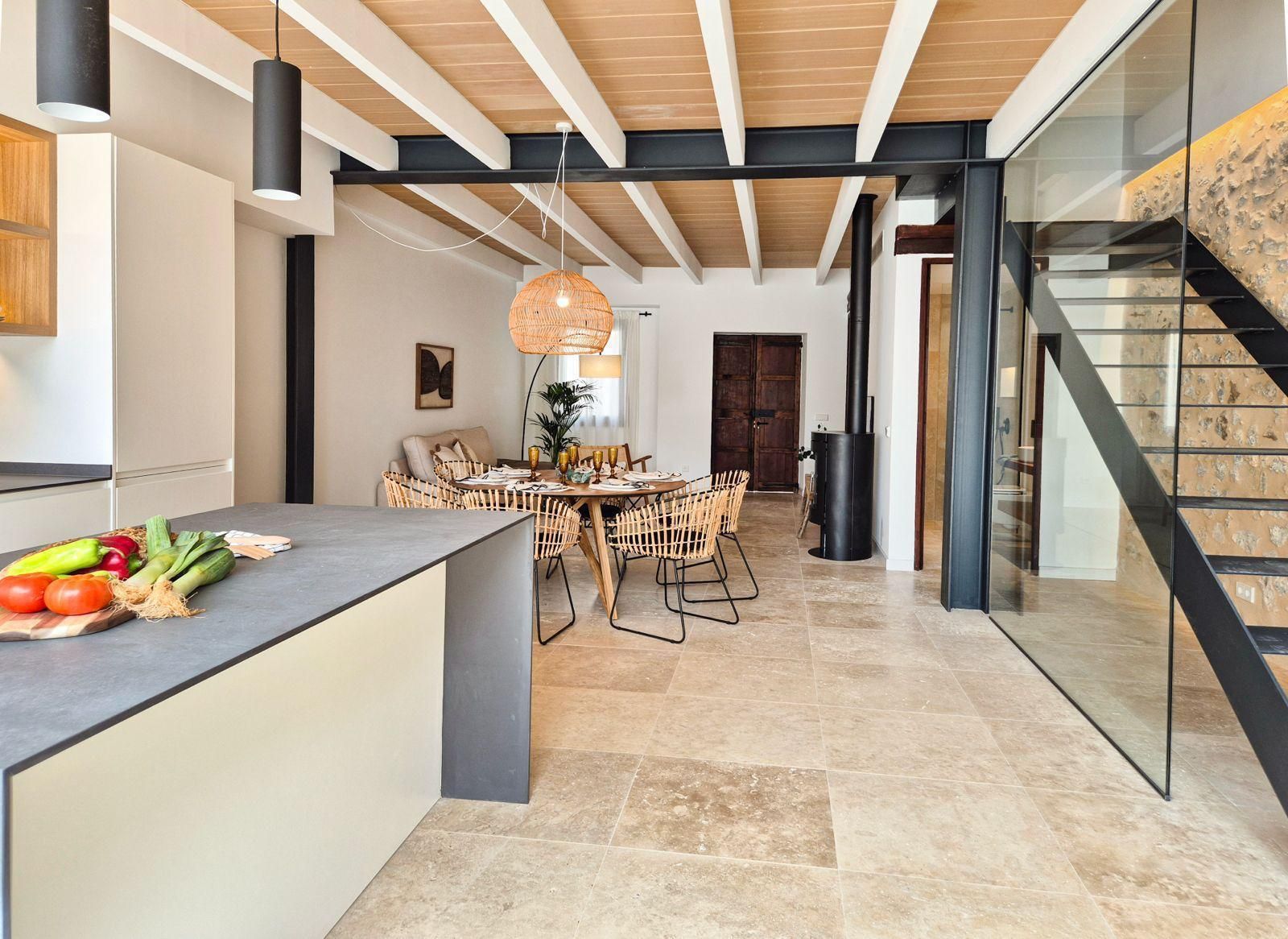 Una cocina y comedor en una casa con pared de cristal y escaleras.