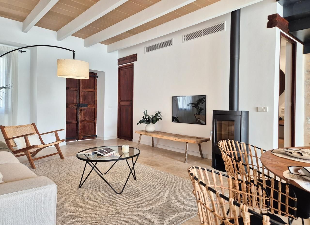 Una sala de estar con un sofá, sillas, una mesa y una chimenea.