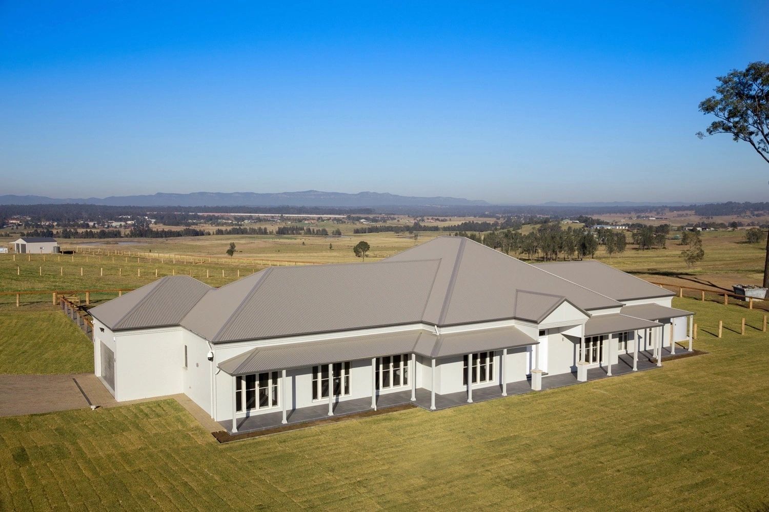 An aerial view of a large white house in the middle of a grassy field.