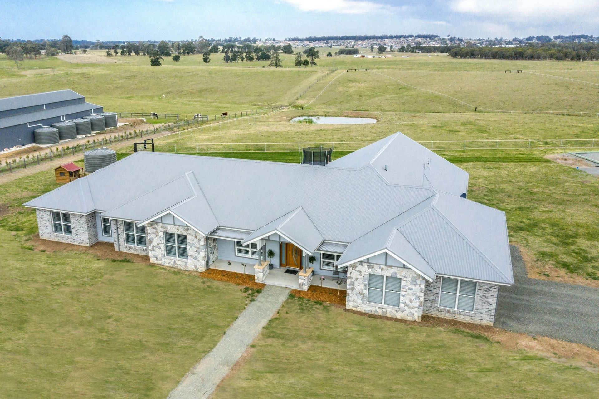 An aerial view of a large white house in the middle of a green grassy field.