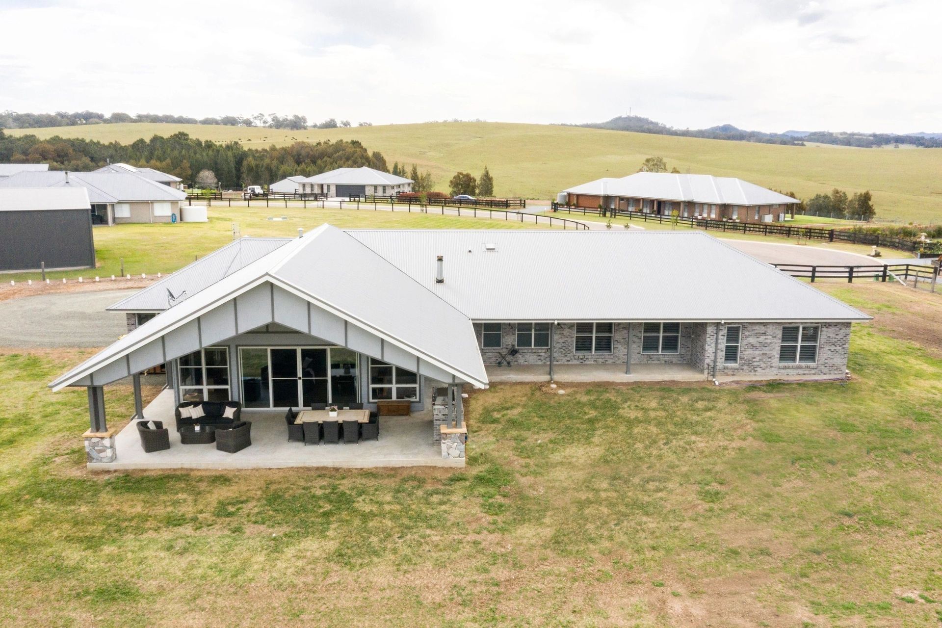 An aerial view of a large house in the middle of a grassy field.