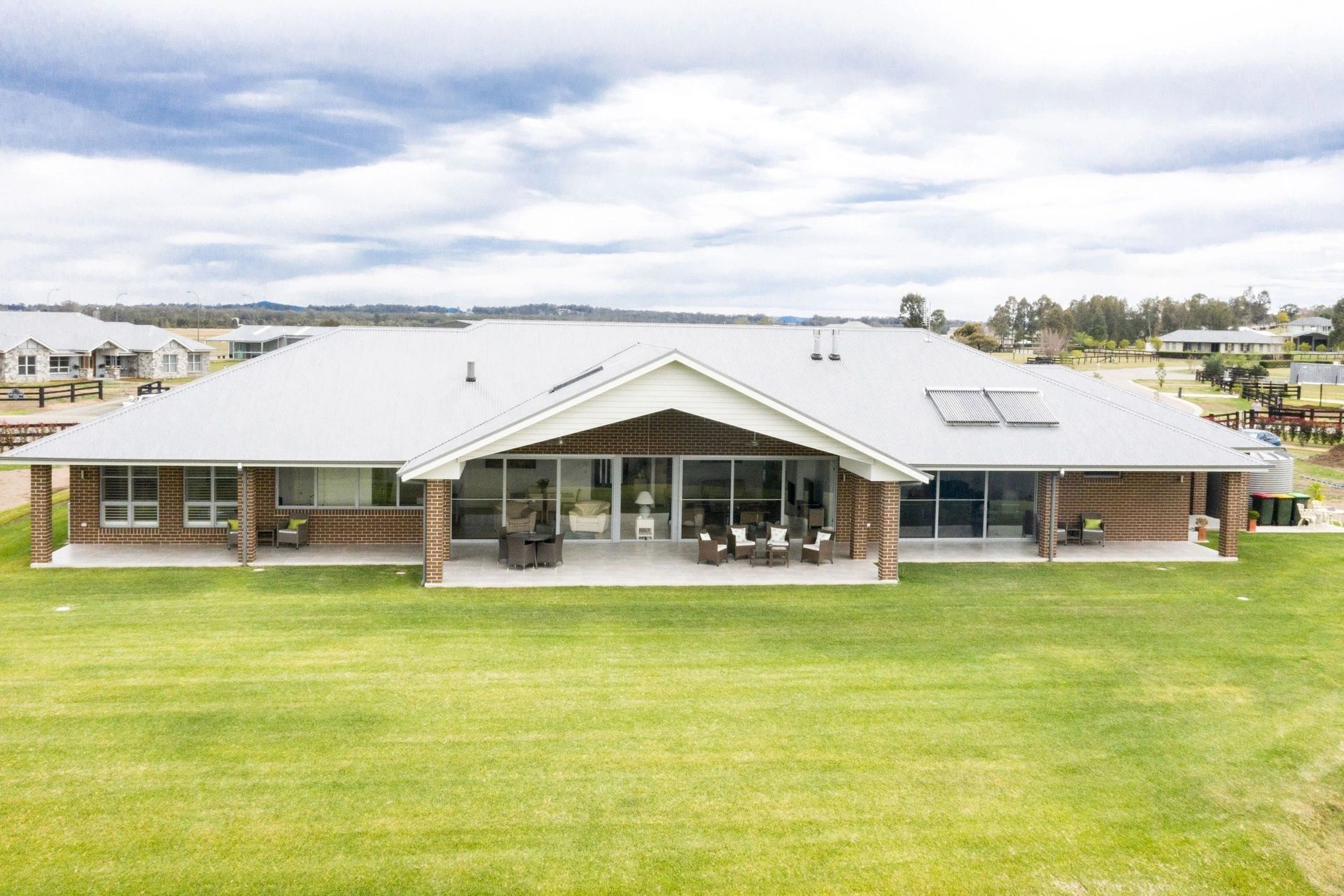 A large house with a white roof is sitting on top of a lush green field.