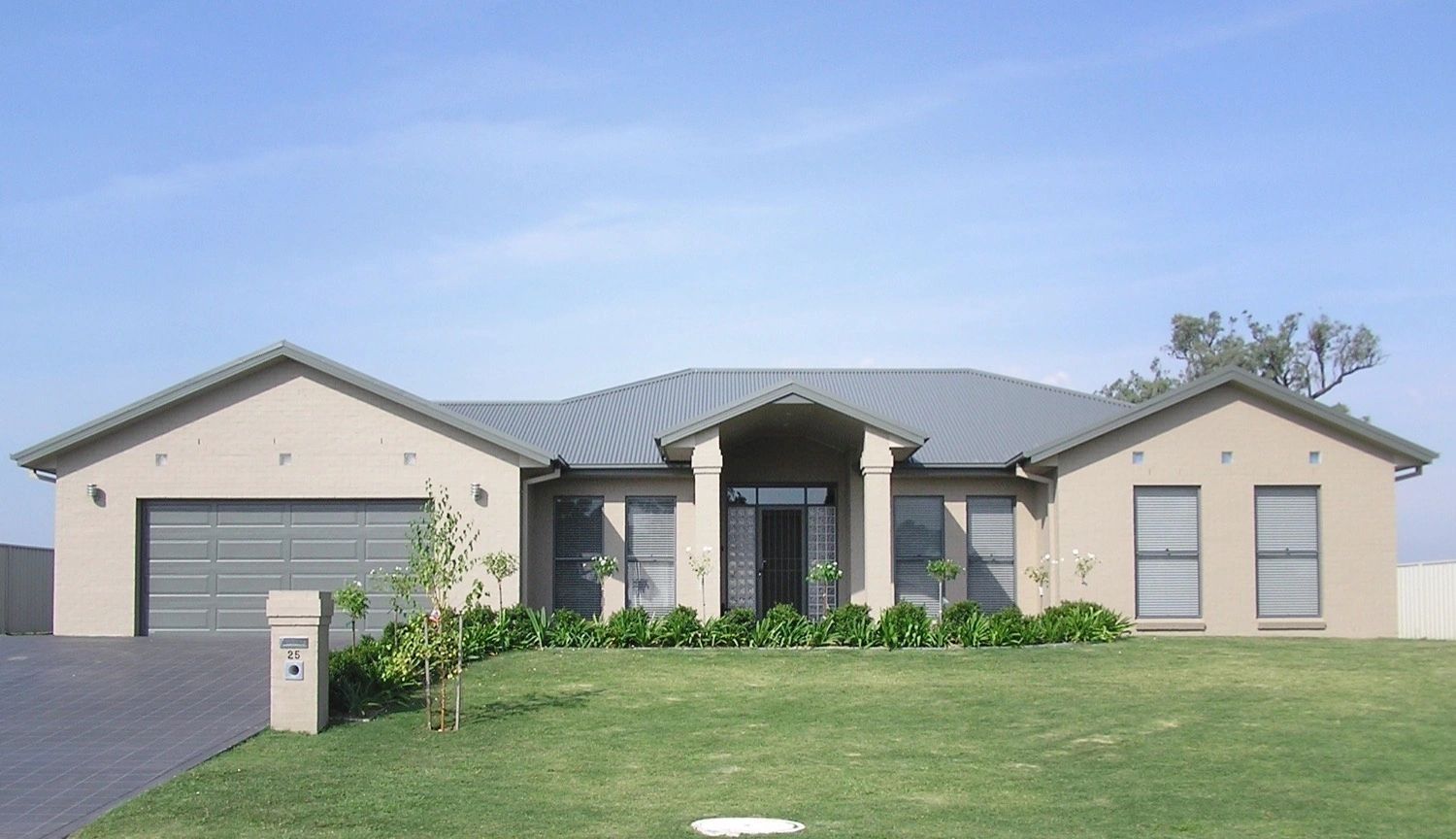 A house with a gray roof has a mailbox in front of it
