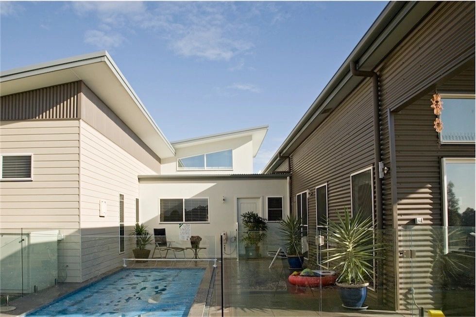 A large swimming pool is surrounded by a glass fence
