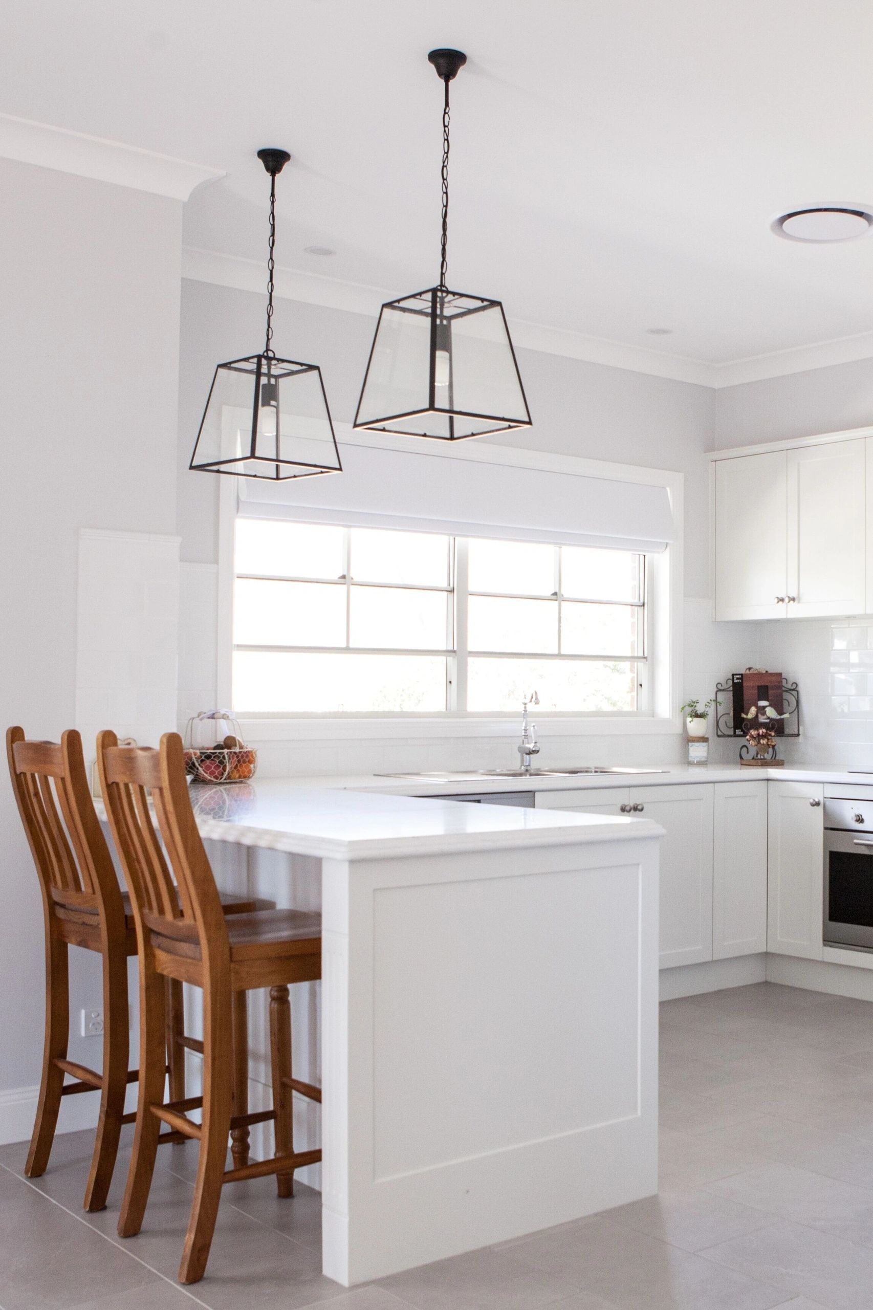 A kitchen with white cabinets and wooden stools