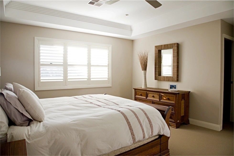 A bedroom with a large bed and a mirror on the wall