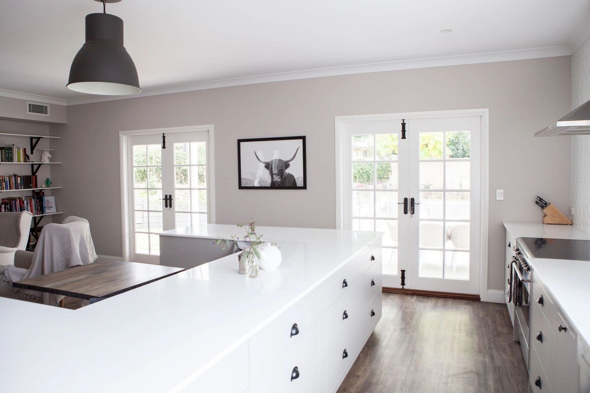A kitchen with white cabinets and a picture of a deer on the wall.