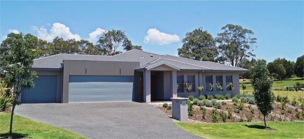 A large house with a driveway and trees in front of it