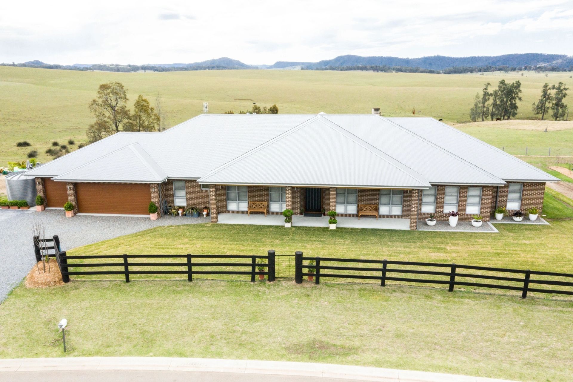 An aerial view of a large house with a fence in front of it.
