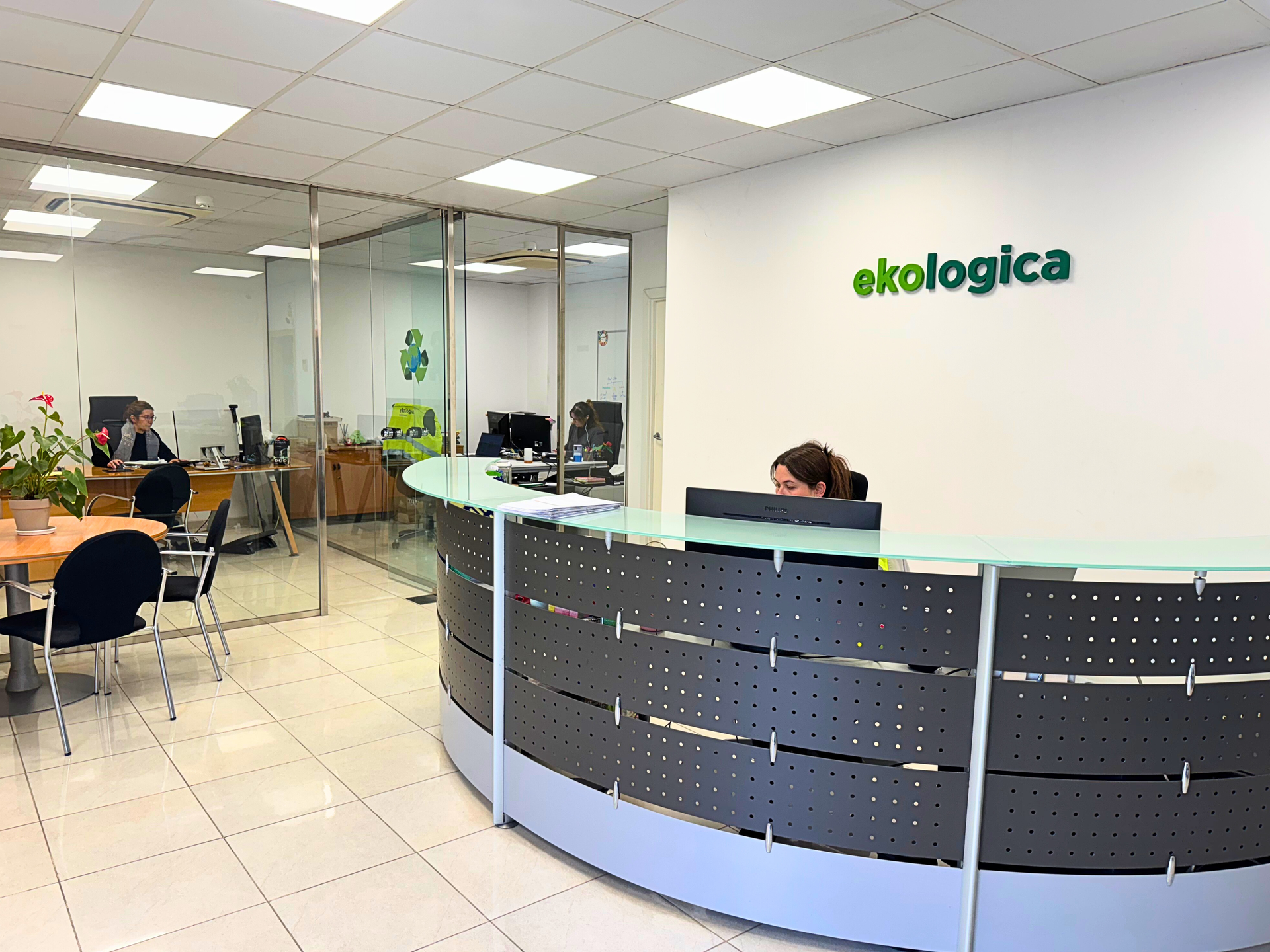 Empleados de oficina revisando datos en una pantalla de computadora. Gráficos y tablas en verde y blanco, escritorio de madera, ambiente moderno.