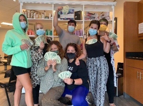 A group of people wearing face masks holding money