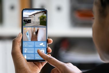 Person using a smartphone app to view home security camera feeds and controls