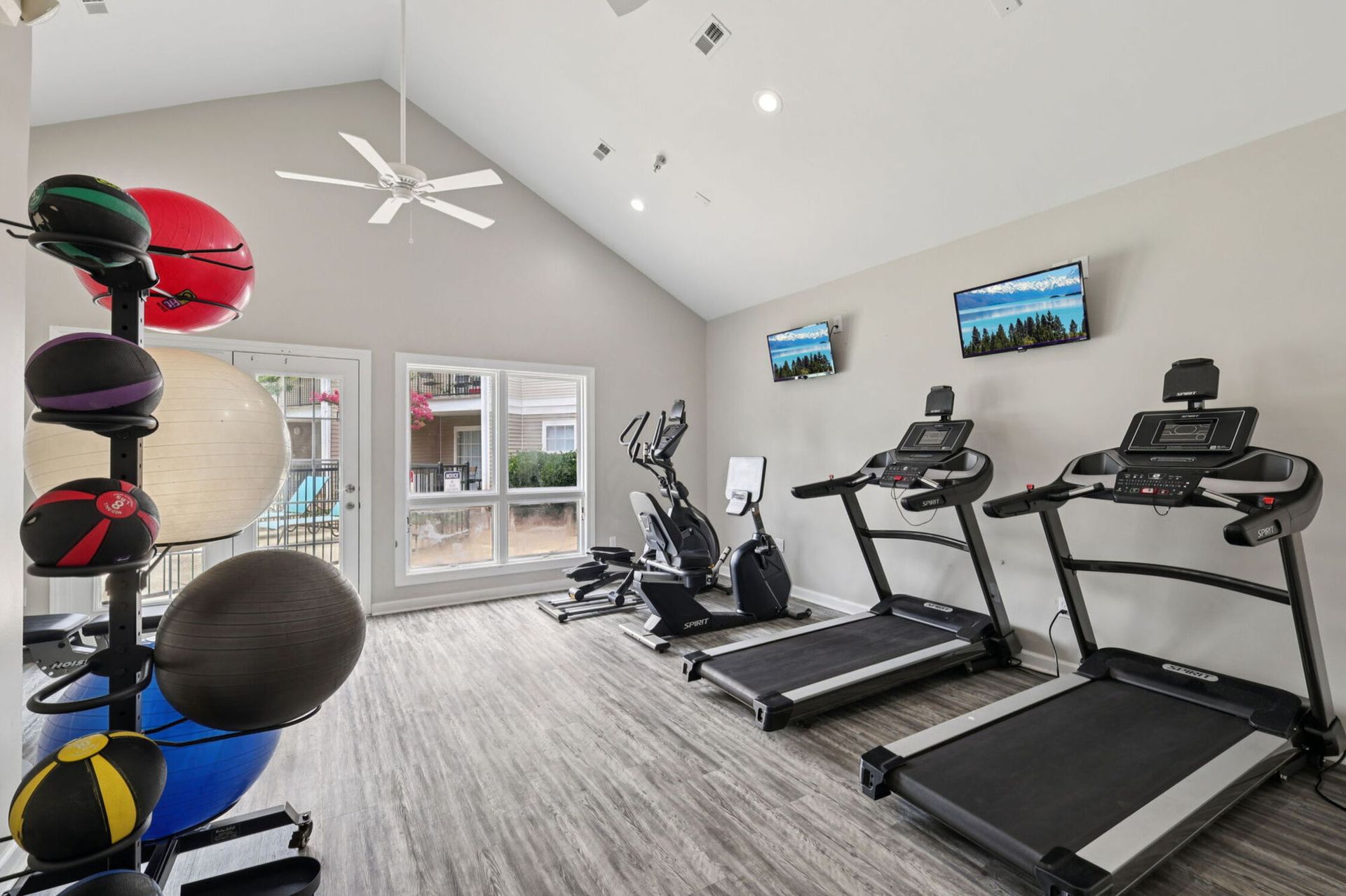 Gym interior with treadmills, exercise bikes, and medicine balls.