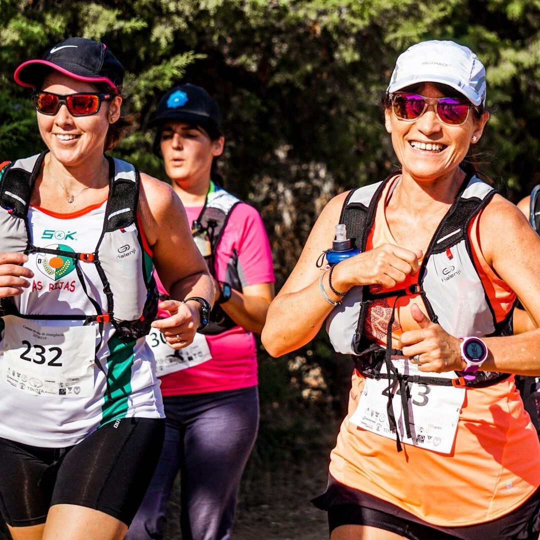 A group of women are running in a race and one of them has the number 232 on her shirt.