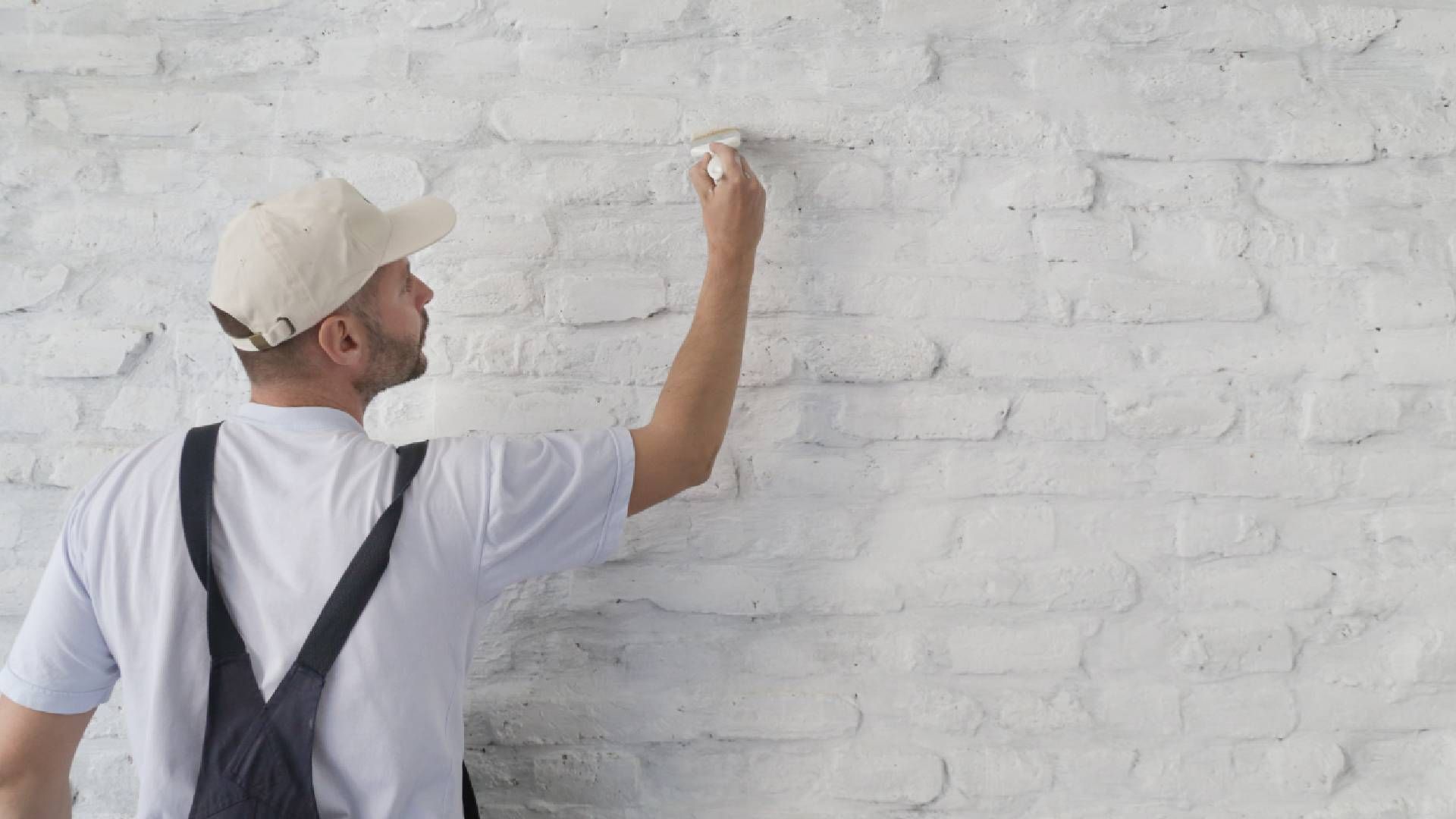 Someone painting a white brick wall with a brush near Holland, Ohio (OH)