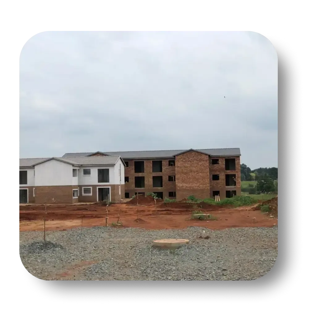 Buildings under construction on a dirt lot; red brick and white siding under cloudy sky.