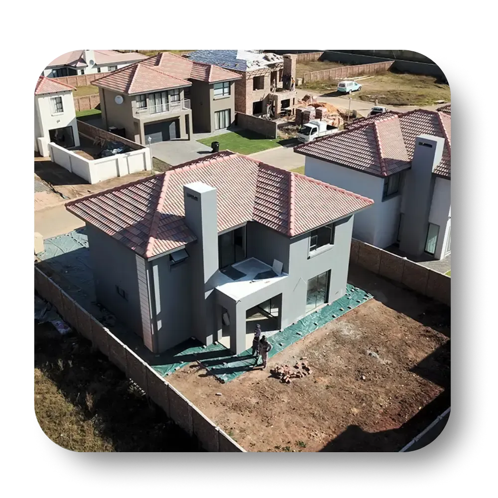 Aerial view of newly built houses, including a gray two-story house with red tile roof.