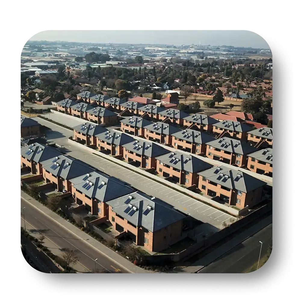 Aerial view of a residential neighborhood with rows of brick townhouses and a road.