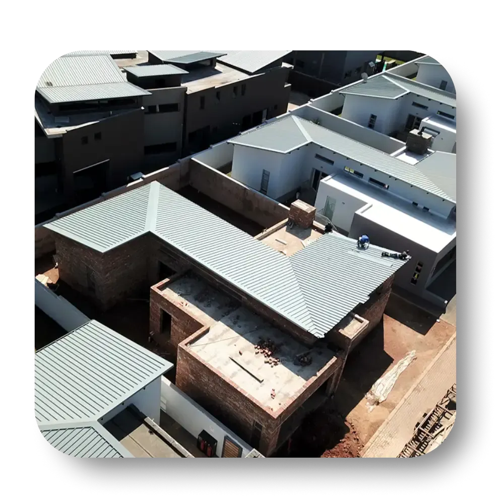 Aerial view of residential construction with corrugated metal roofs and brown brick walls.