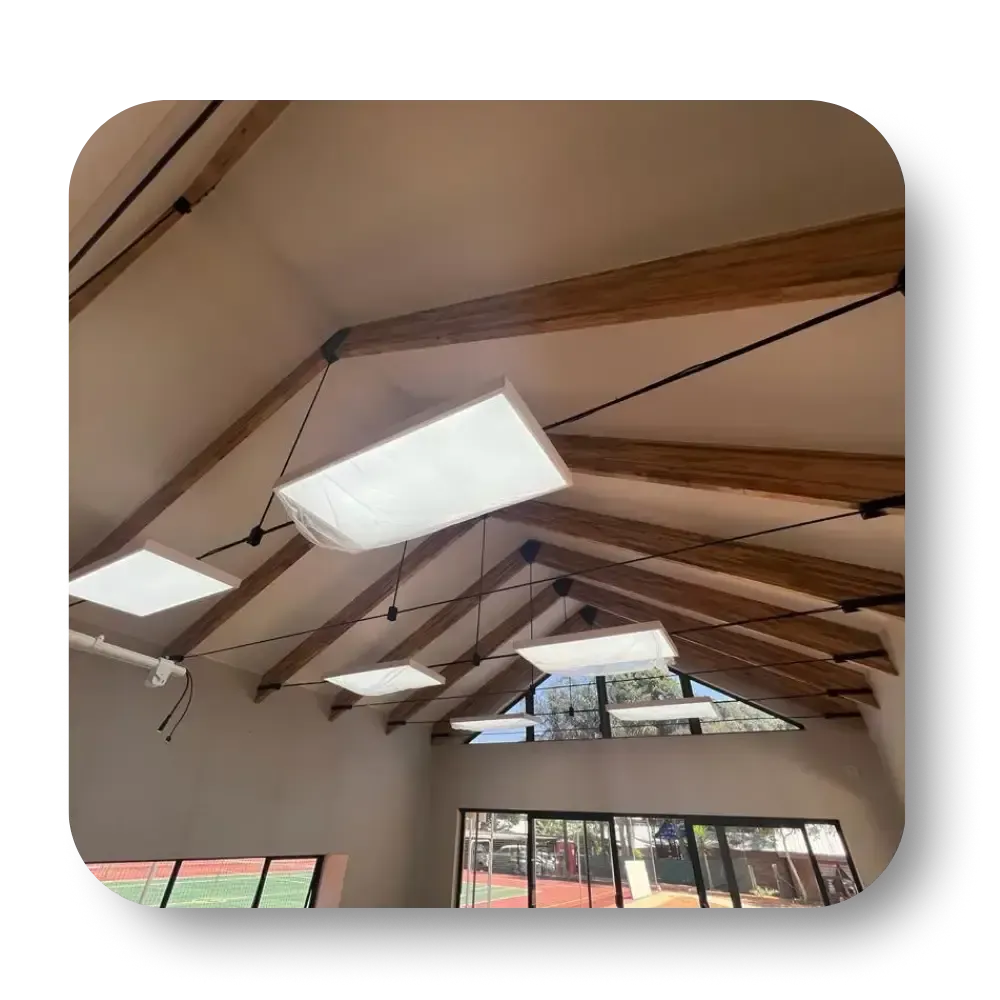 Beamed ceiling with hanging rectangular lights, in a room with a glass wall overlooking a tennis court.