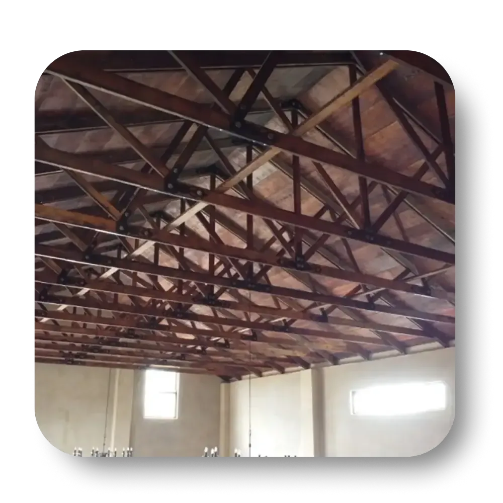 Wooden roof trusses inside a building. Natural wood color; white walls, windows.