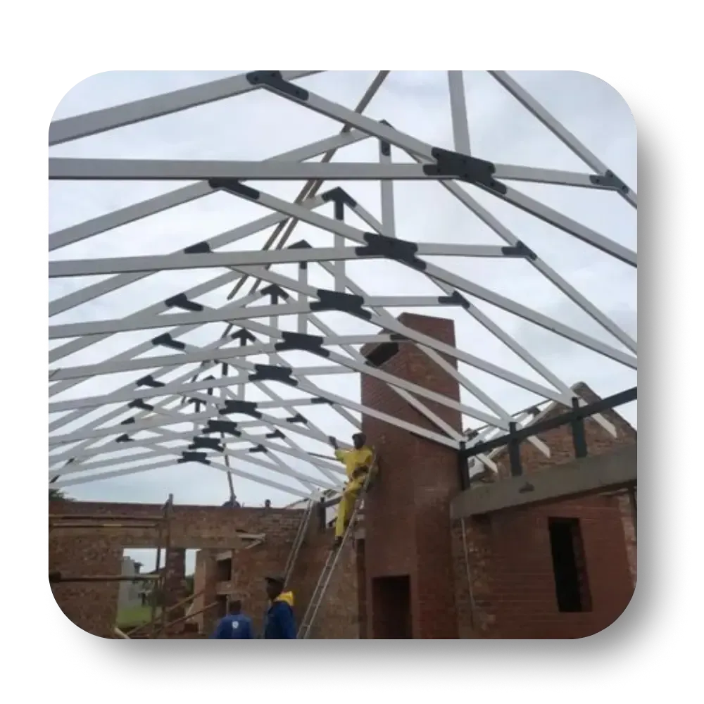 Roof truss construction over a brick building, with workers in yellow and blue.