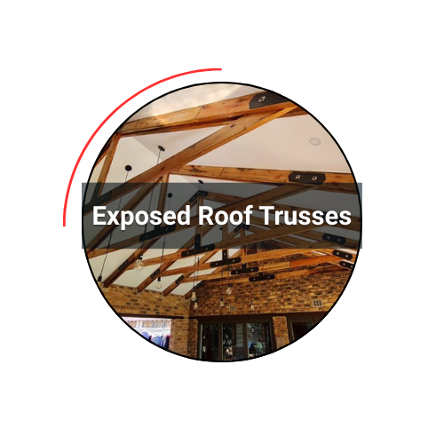 Exposed roof trusses in a building, with wooden beams, a brick wall and exposed lighting.