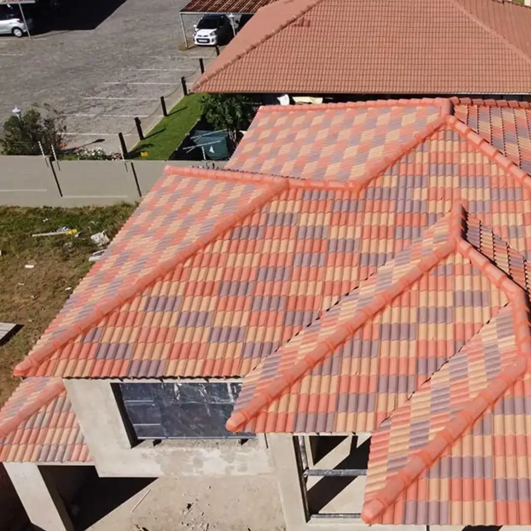 Red, orange, and gray tiled roof of a building under construction. Adjacent building with brown roof.