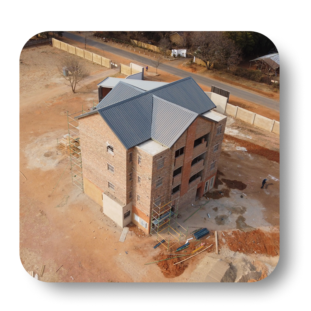 A brick building under construction with a gray roof.