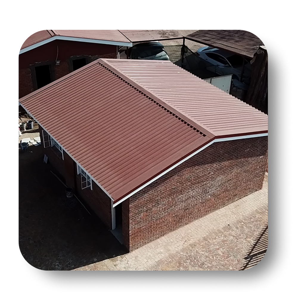 Brown brick building with a brown corrugated metal roof, white trim.