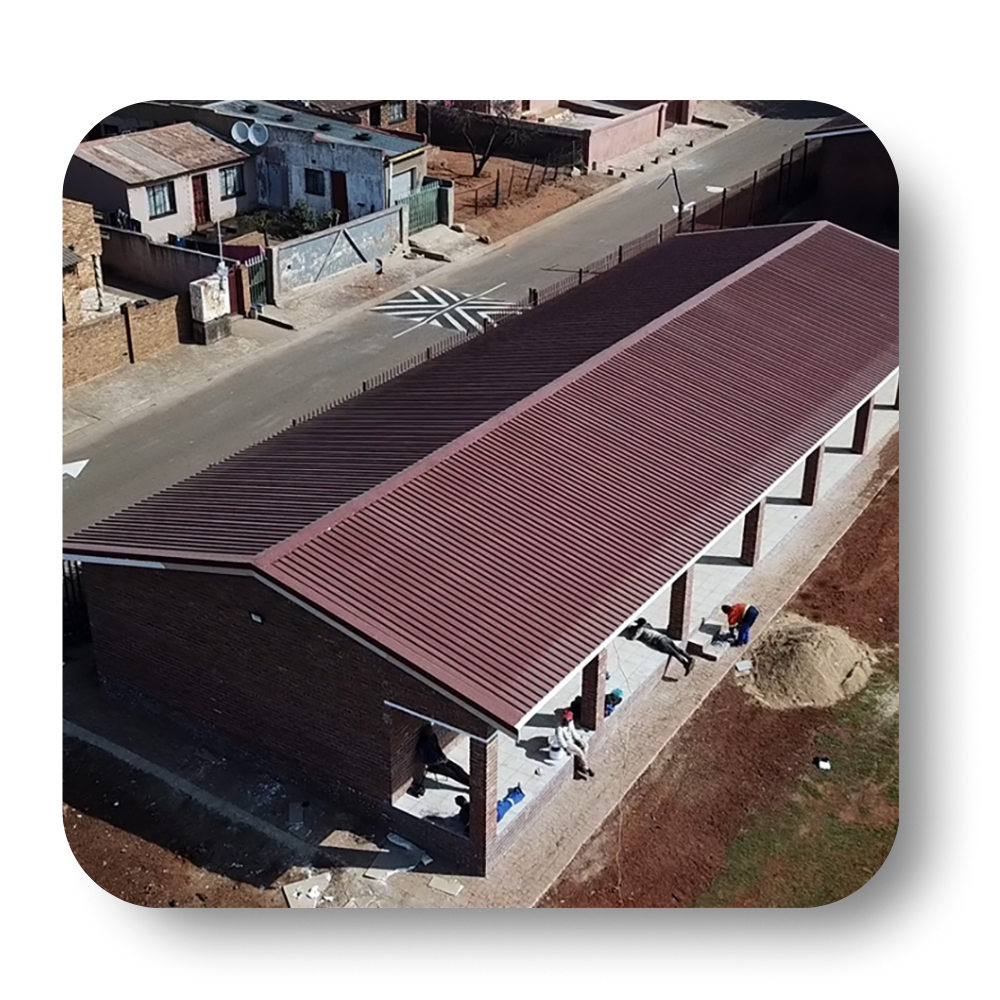 Brown-roofed building in a neighborhood; construction workers on site.