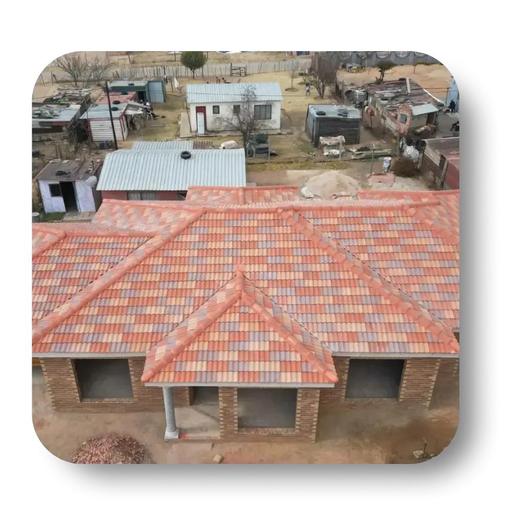 An aerial view of a new brick house with a colorful tiled roof in a rural setting.