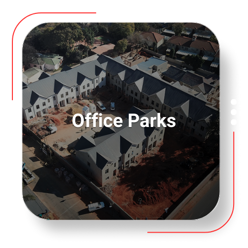 Aerial view of an office park under construction, with white buildings and gray roofs.