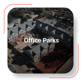 Aerial view of an office park under construction, with white buildings and gray roofs.