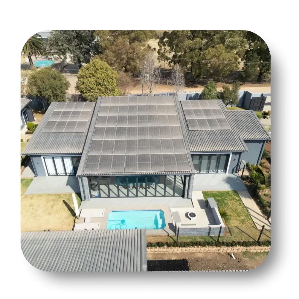 Aerial view of a modern house with solar panels, a pool, and a lush green yard.