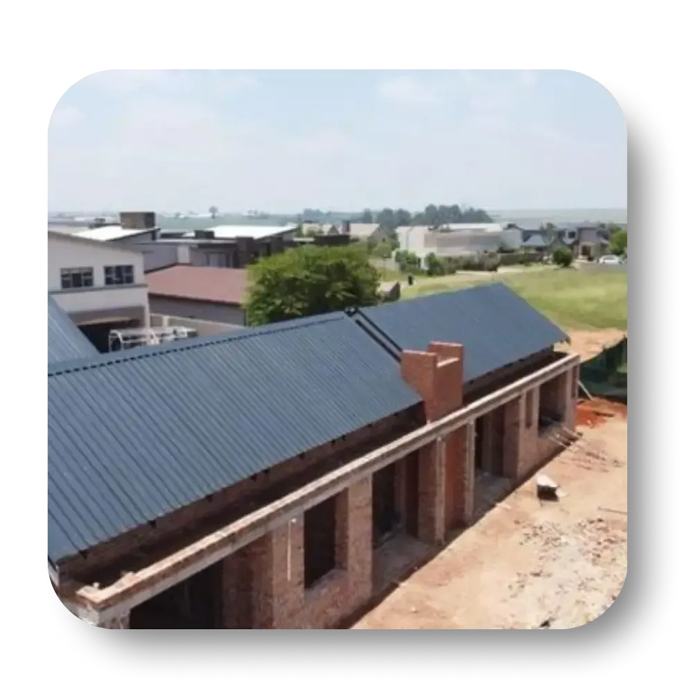 A partially built brick house with a dark blue roof under a sunny sky.