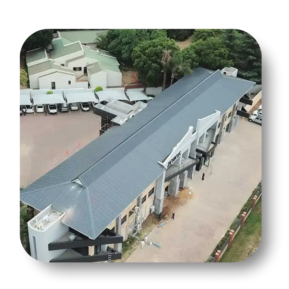An aerial view of a long, grey-roofed building with a courtyard.