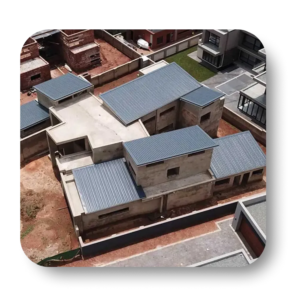 Aerial view of a modern home under construction, featuring flat gray rooftops and exposed concrete walls.