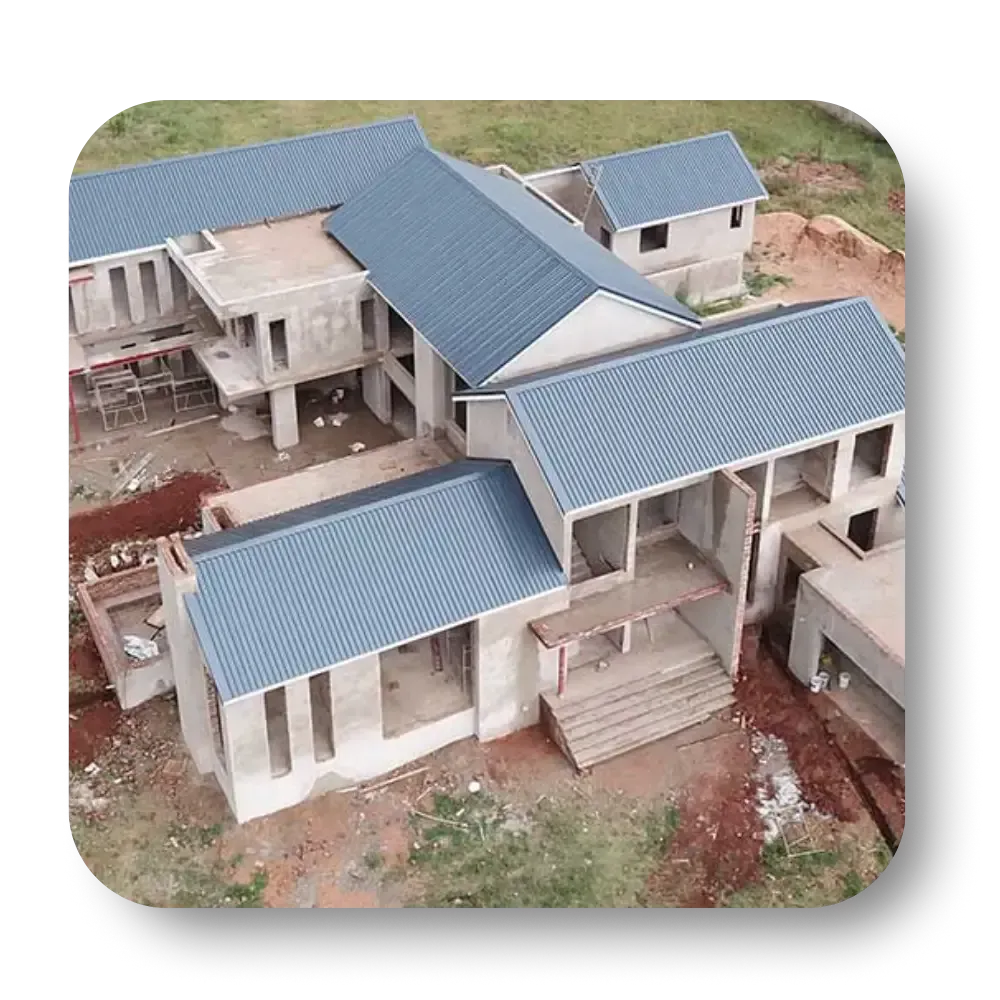 Unfinished multi-story concrete building with blue metal roofs. Construction site, aerial view.