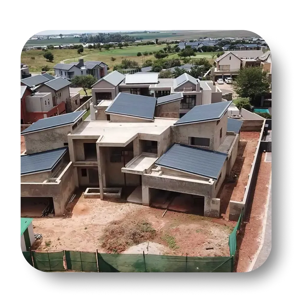 Modern multi-story house under construction with gray roof tiles, in a residential area with other houses.