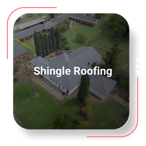 Aerial view of a house with gray shingle roofing, surrounded by trees and lawn.