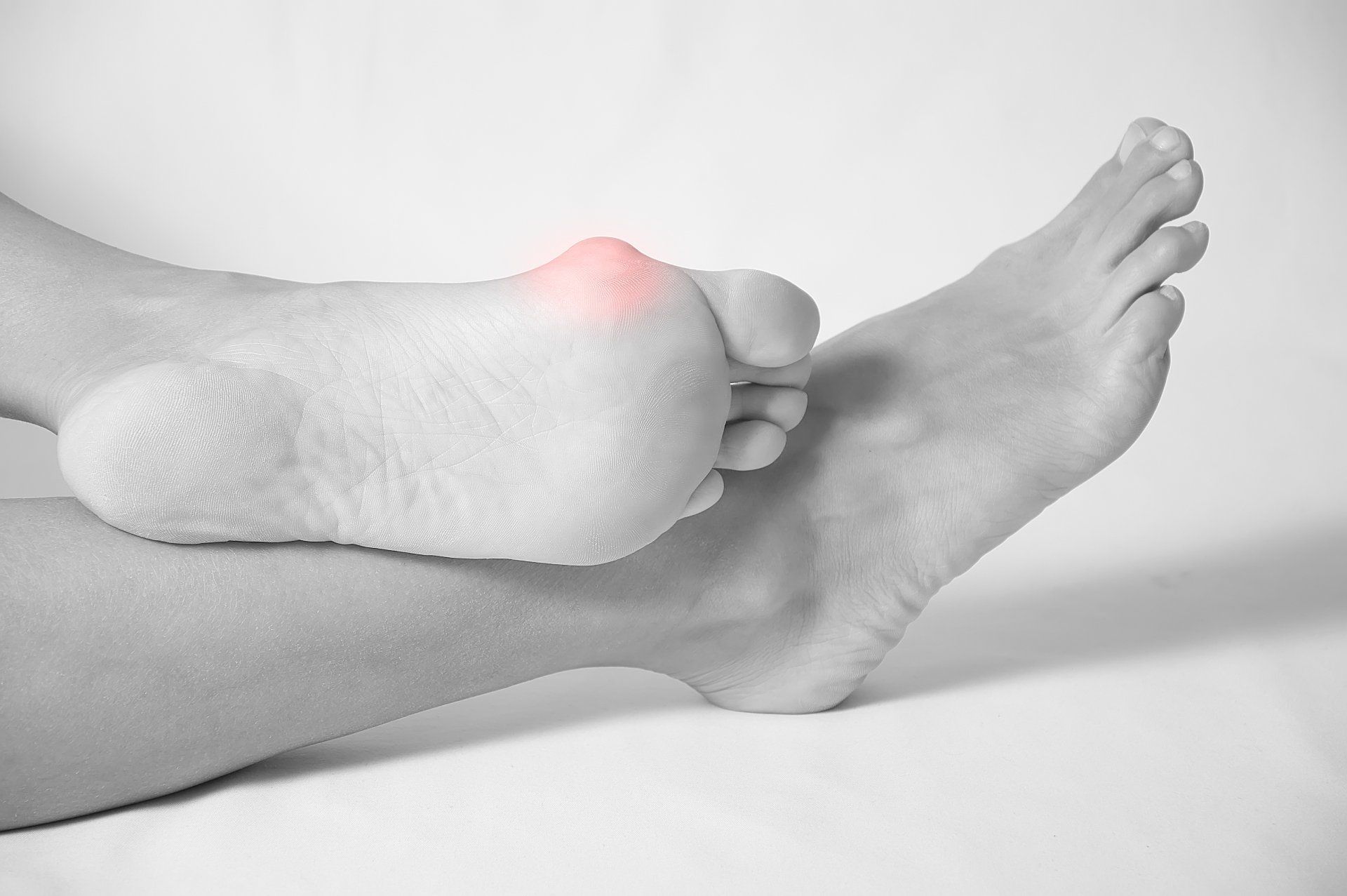 A black and white photo of a person 's foot with a red spot on it.