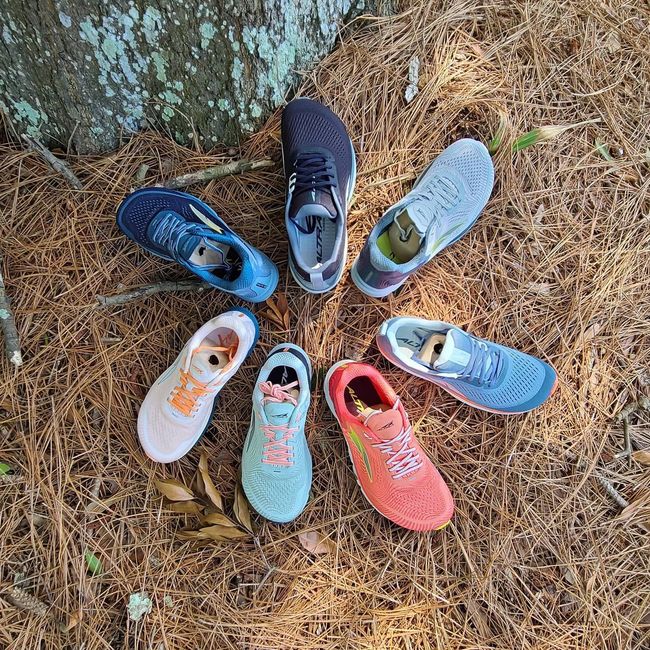 A group of shoes are sitting in a circle on the ground.