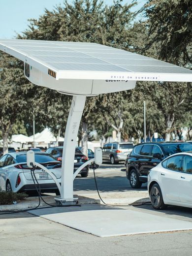 Solar-powered EV charging station with cars plugged in, outdoors on a sunny day.