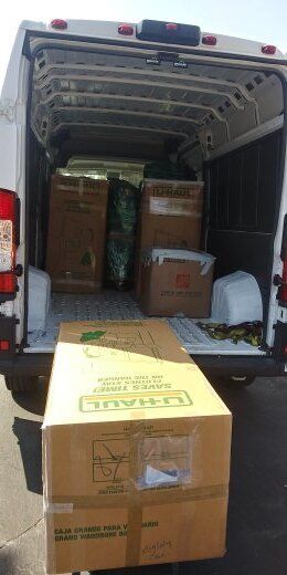 A U-Haul box is being loaded into a white van with boxes already inside.