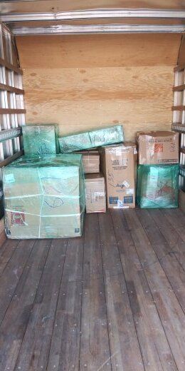 Boxes packed inside of a truck, with wood flooring and walls.